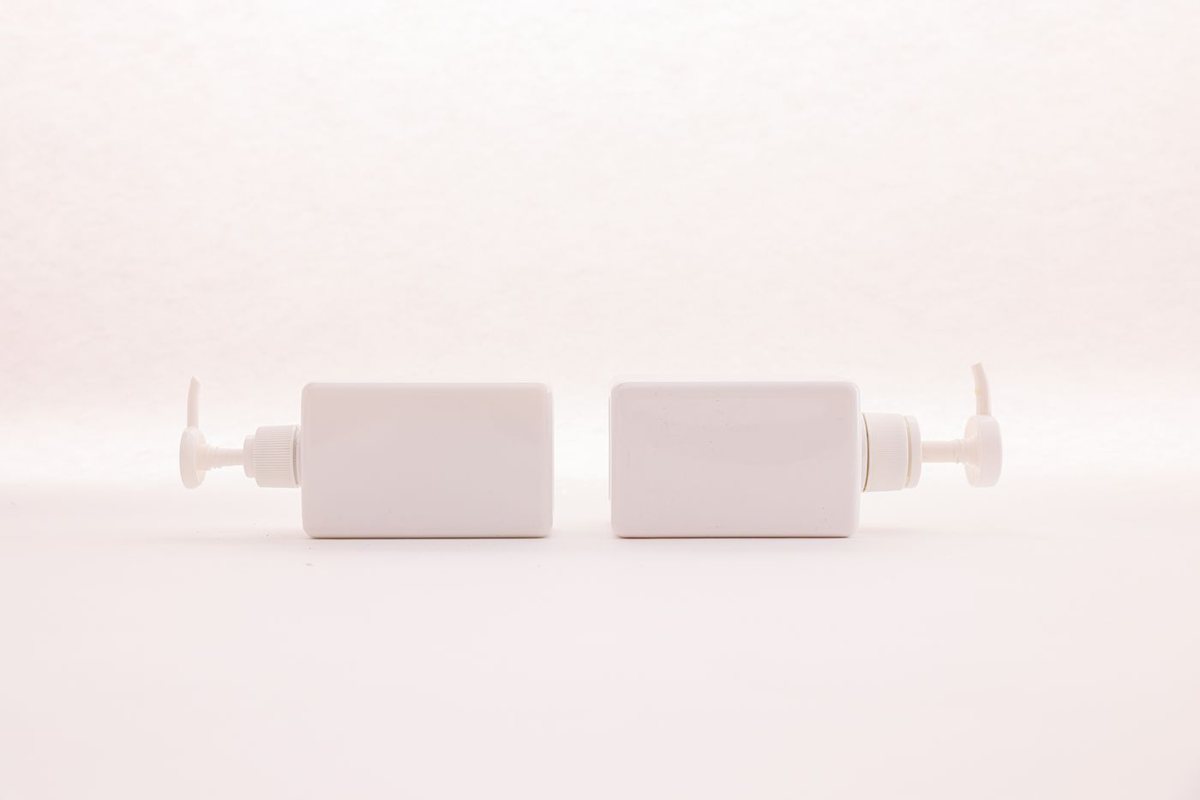Two plain white pump bottles with blank, unbranded labels on a white background.